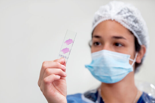 Young female scientist preparing slides with paraffin-embedded sections for pathological analysis.