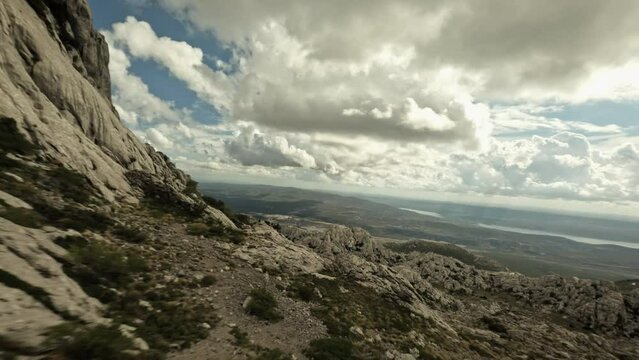 Drone flying past female hiker at Tulove Grede in the Velebit mountains, Croatia