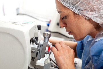 Young female scientist works on a rotary microtome to obtain sections from a paraffin-embedded specimen.