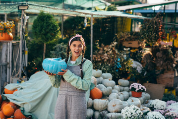 Female farmer holding blue colored pumpkin, decorated pumpkin for holiday.