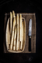 Asperges blanches dans une barquette en bois et un couteau, vu de dessus