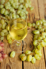glass of wine with grapes on wooden table