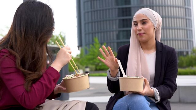 Young multiracial business women eating together healthy poke food during lunch break outside of office	