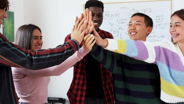 Young multiracial students stacking hands inside school class room