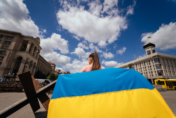 Fototapeta na wymiar Young woman carries the flag of Ukraine fluttering behind her