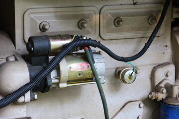 Old starter motor with wires. Close-up details of the starter motor set are mounted on the side of...
