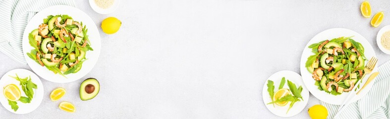 Flat lay of Healthy salad plate. Fresh seafood recipe. Grilled shrimps and fresh vegetables (avocado, arugula, mango) on gray concrete background. 