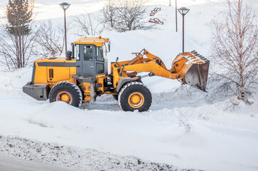 Snow clearing. Tractor clears the way after heavy snowfall. A large orange tractor removes snow...
