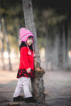 Portrait of cute asian little girl wear Winter clothes at the forest of the park,Thailand people pose for take a picture,Happy time