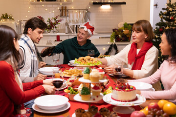Multi-ethnic family having fun and enjoying indoor party on dinner table at home, New Year party or Christmas day