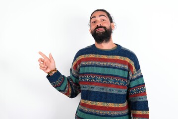 Naklejka premium Positive Caucasian man with beard wearing sweater over white background with satisfied expression indicates at upper right corner shows good offer suggests to click on link