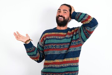 Fototapeta premium Shocked amazed surprised Caucasian man with beard wearing sweater over white background hold hand offering proposition