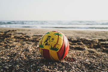 beach volleyball ball stands on the sand on the beach, sea is blurred in back