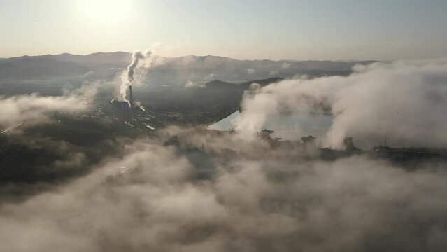 View from above. A small village shrouded in fog in Russia. Chimney GRES smokes over the Soviet village. Ecological air pollution.