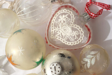 White and transparent Christmas tree ornaments, illuminated by sunlight. Flat lay.