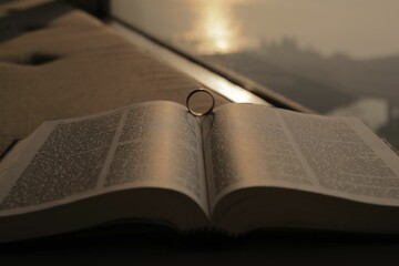 Closeup of a ring resting in between the pages of an open bible at sunrise in Mumbai