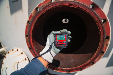 Worker hand holding gas detector inspection safety gas testing at front manhole tank