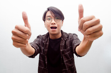 Young Asian man smiling happily and giving thumbs up as compliment