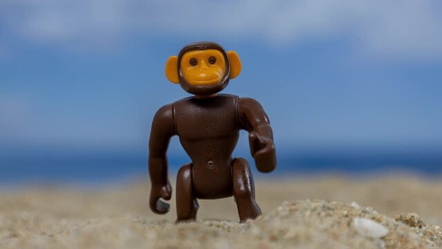 A toy monkey on a sandy beach 