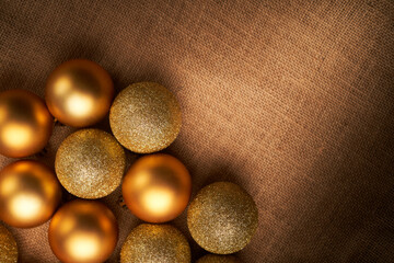 golden christmas balls with different textures and glitters on sackcloth with space for copy