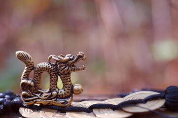 Dragon figurine with Chinese coins close-up on a colored background. East Asian culture. A spiritual symbol.