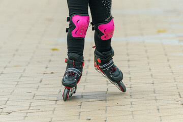 Fototapeta na wymiar Legs of a child rollerblading in the park