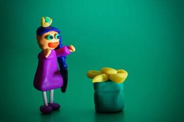 A plasticine toy girl with a gift on a green background.