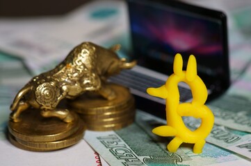 A metal bull with coins and a bitcoin sign on the table. Business concept. Financial symbol.