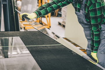 The glazier places a pane of glass on a specialized table, Work in a glass factory
