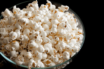 Popcorn on a black background. Top view of the popcorn. Popcorn in a glass bowl