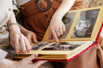 Mom and daughter are considering a family photo album. An elderly woman and young girl hold a...