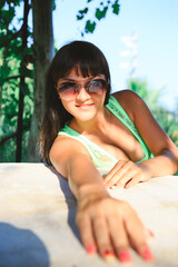 A young brunette woman sits at a table with her arms outstretched forward. Young woman at a table...