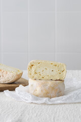 French soft strong smelling cheese Munster on white paper on light rustic background, selective focus