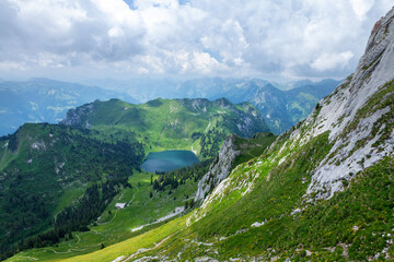 Panoramic view of lake, green alpine meadows and mountains