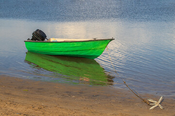 A small boat with a motor is anchored on a beach in the sea.