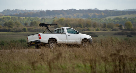white toyota hilux pickup truck converted with an army large calibre machine gun on the rear deck