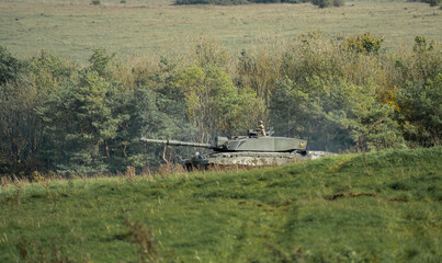 British army Challenger II 2 FV4034 main battle tank in action crossing open grass fields, on a...