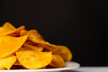 Delicious crispy potato chips with spices on a black background, place for text