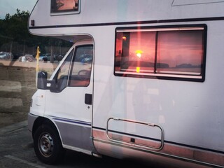 Sonnenuntergang am roten Himmel spiegelt sich im Fenster des Reisemobils