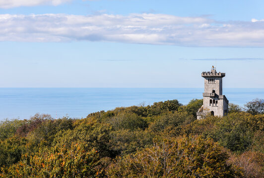 An old castle against the blue sky, the sea and the city. The tower on Mount Akhun in Sochi, Russia.