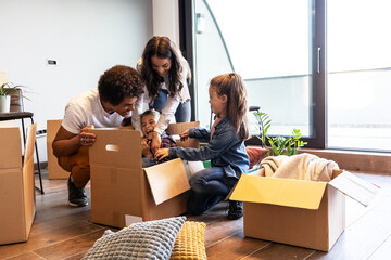 Mixed race family moving into their new home. They're unpacking and having fun together.