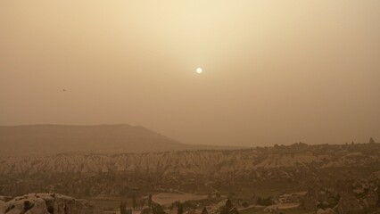 Fototapeta na wymiar Sunrise sky in dust after sandstorm over rocky mountains valley in Cappadocia