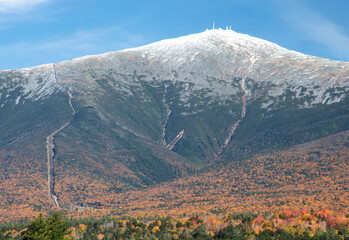 Blue sky and colorful fall foliage with dusting of snow atop summit of Mount Washington in New Hampshire. Visible on left are tracks of cog railway with antenna of weather observatory on summit. - obrazy, fototapety, plakaty