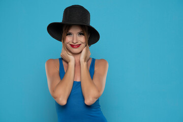 Smiling young woman with black summer hat on a blue background