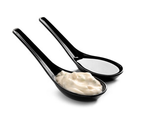 Caesar salad dressings in black spoons on white background