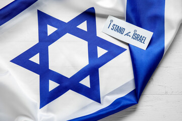 Flag of Israel and card with text I STAND FOR ISRAEL on white wooden background