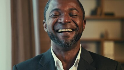 Close-up adult happy african american man laughing with funny joke feels genuine emotion carefree smiling businessman winner having fun sincere laughs good mood receives humorous news standing indoors