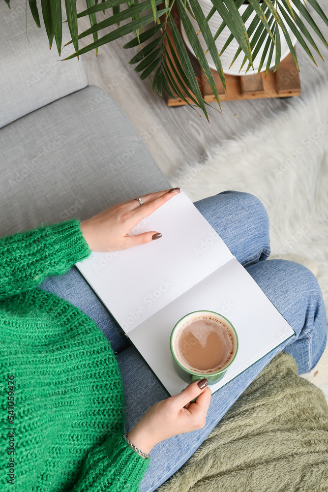 Wall mural woman with cup of coffee and book at home, closeup