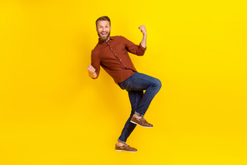 Fototapeta na wymiar Full size photo of impressed handsome man blond beard burgundy shirt clench fists up shout yeah isolated on yellow color background