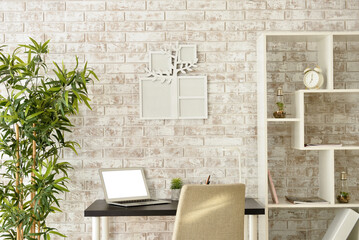 Cozy interior of modern workplace with laptop and family tree photo frame